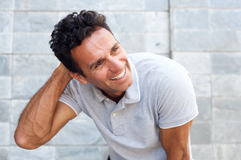 Handsome older man laughing with hand in hair